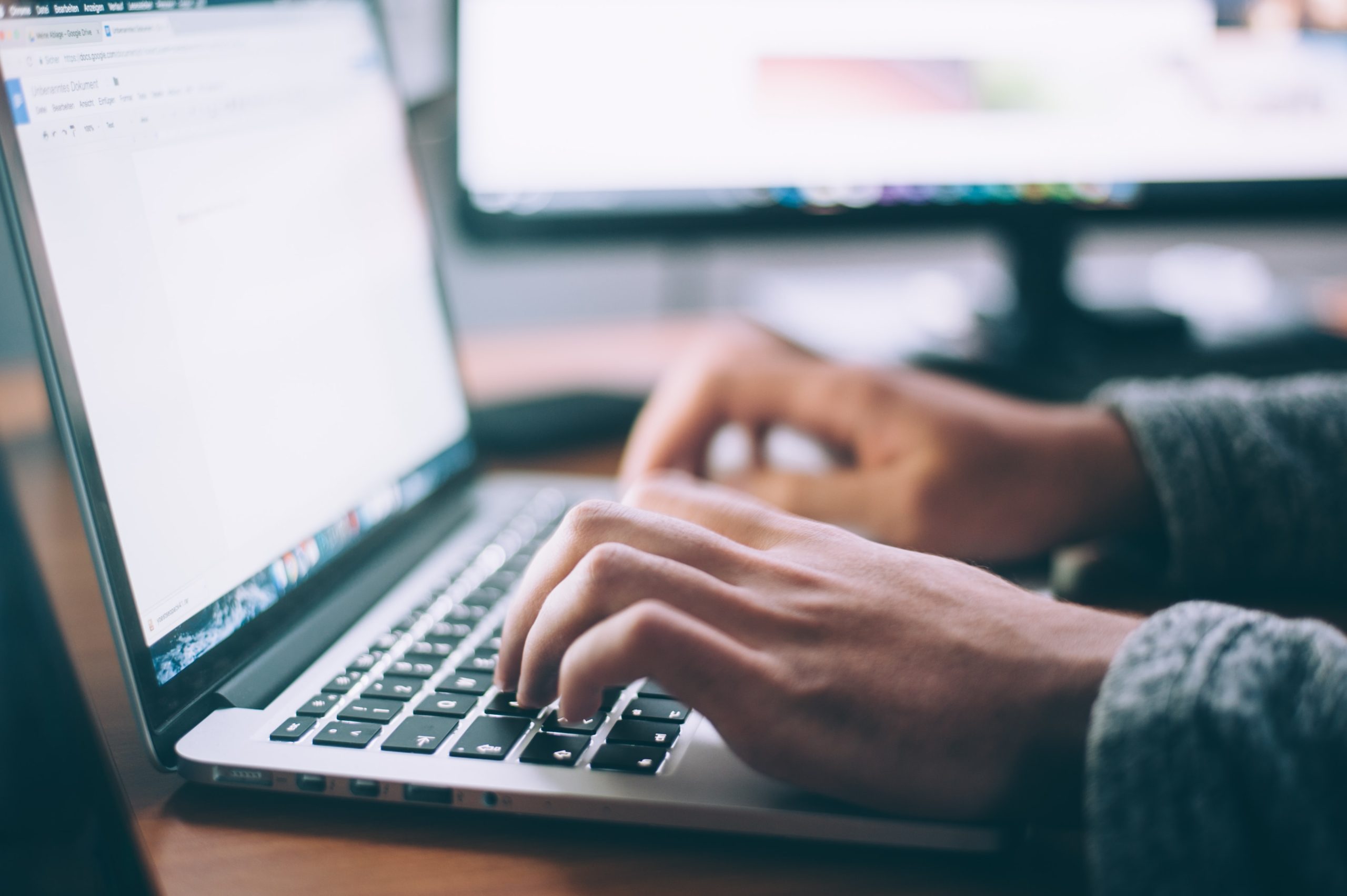 hands typing on keyboard of laptop. screen is not visible