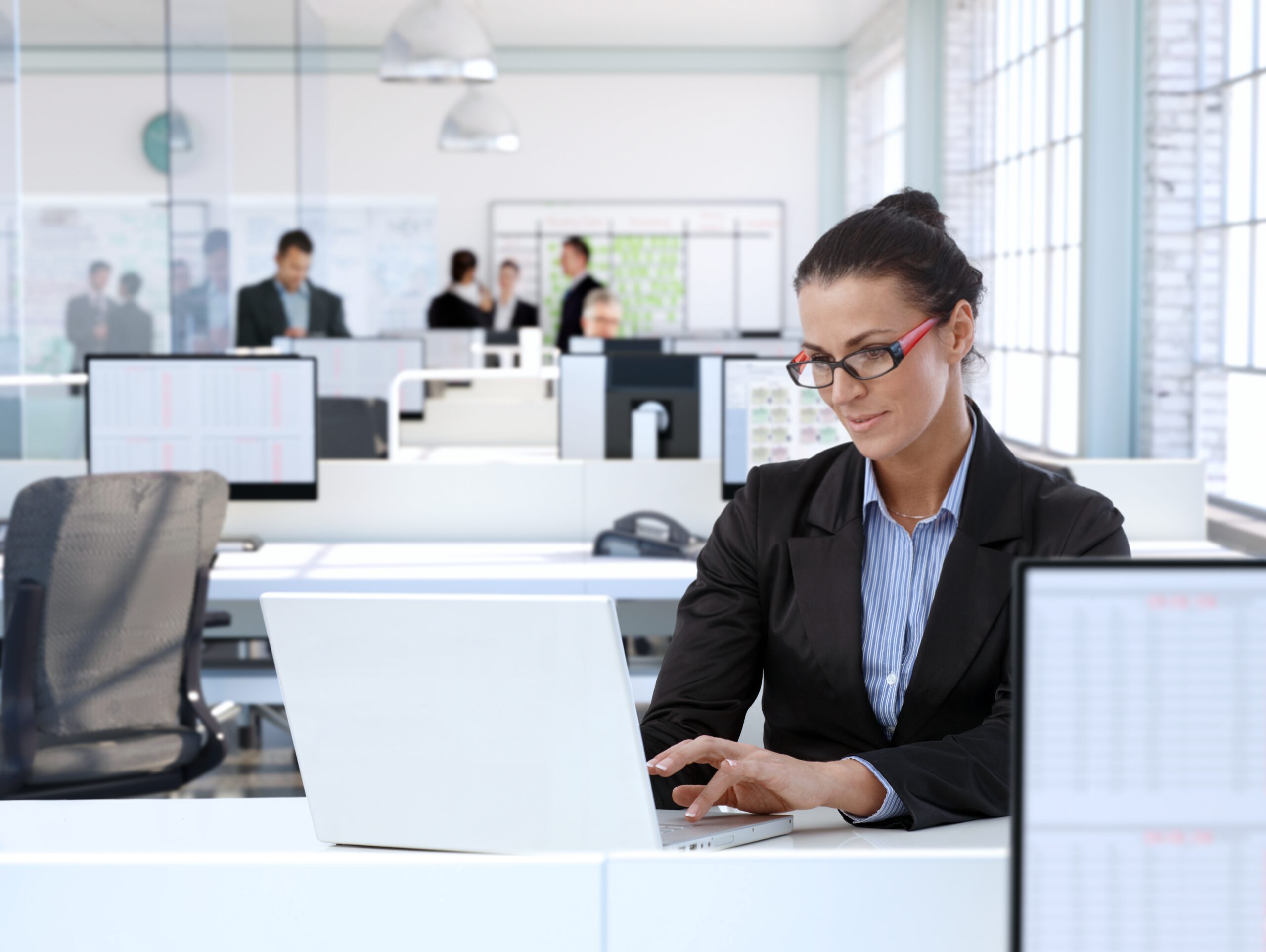 Trustworthy businesswoman working at office desk, using laptop computer.